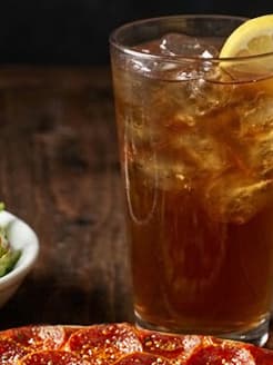 A tall glass of Donatos fresh-brewed iced tea over ice, garnished with a lemon slice